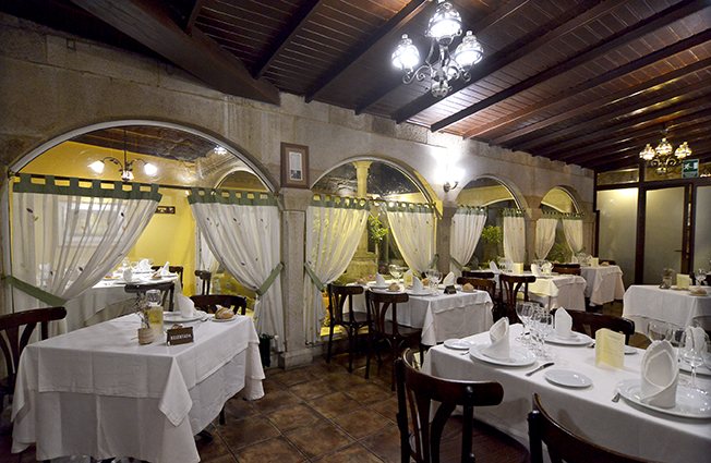 Comedor de Casa Rosalía bajo los arcos, con las mesas puestas