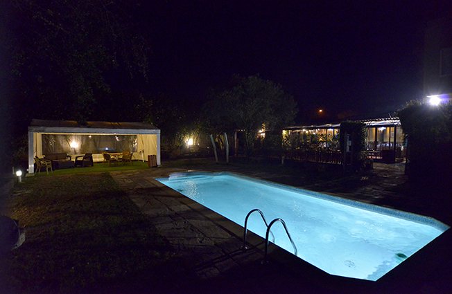 El jardín y la piscina del hotel iluminados de noche